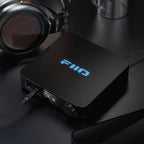 FiiO K11 headphone amplifier and DAC, in black, lifestyle setting