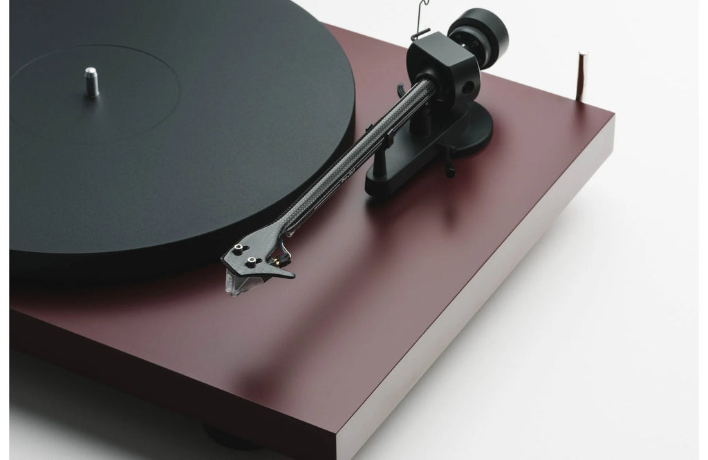 Pro-Ject Debut EVO 2 turntable with black plinth, silver tonearm, and clear acrylic platter on a wooden surface.