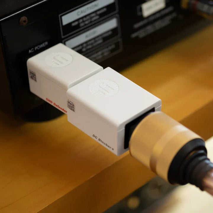 SilentPower DC Blocker+ noise filter displayed with a sleek design and connectors visible on a slate background.