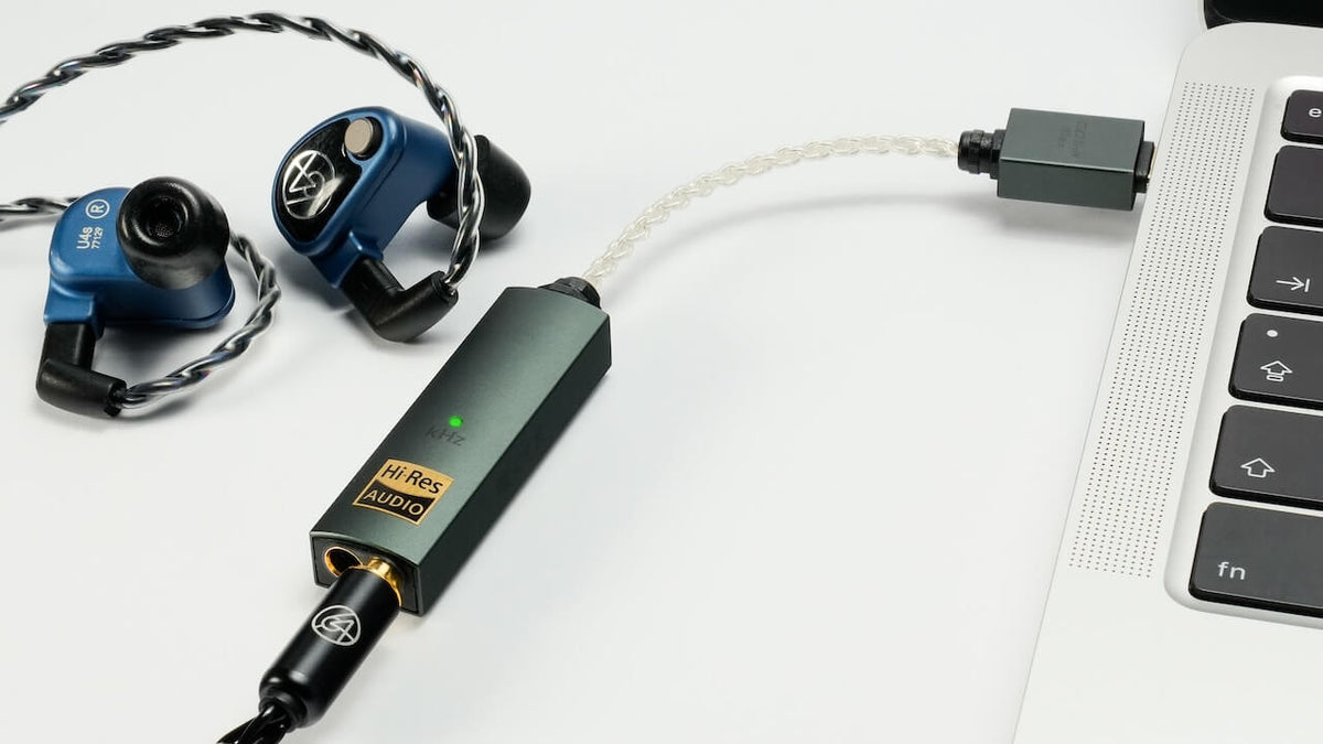 iFi Audio Go Link Max headphone amplifier and DAC dongle connected to a laptop for high-quality audio.