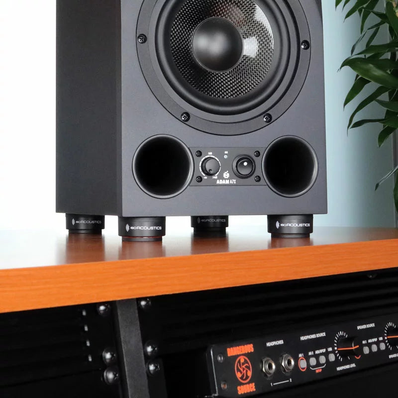 IsoAcoustics ISO-Puck Mini studio monitor stand isolators on a surface, designed to reduce vibrations and improve sound clarity.