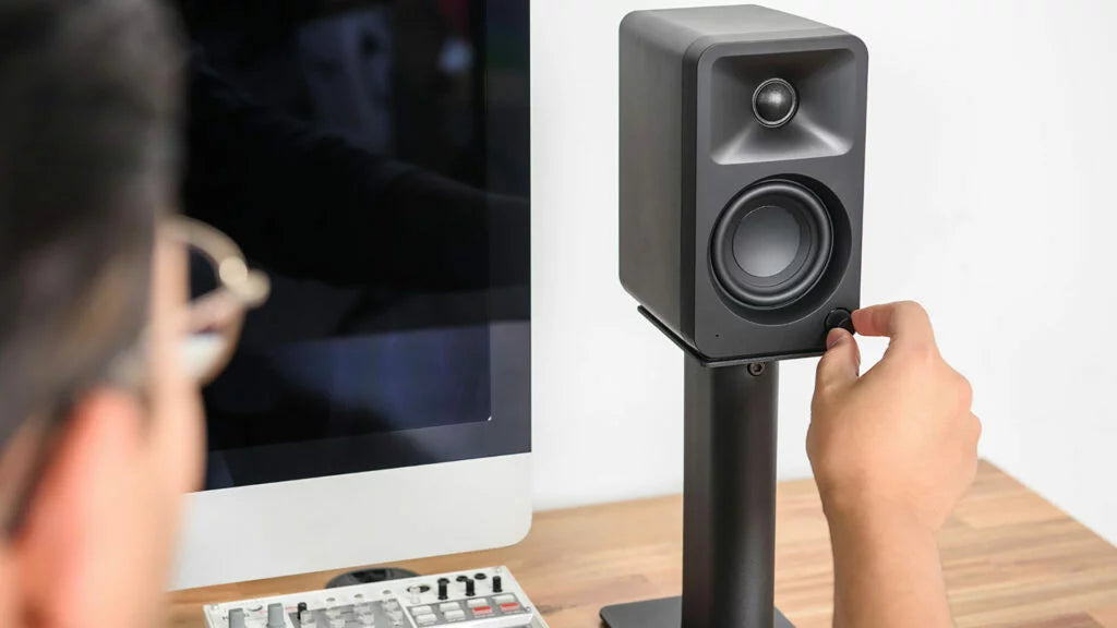 Kanto Audio Ora desktop speakers on stands, with sleek black design and modern audio equipment for high-quality sound.