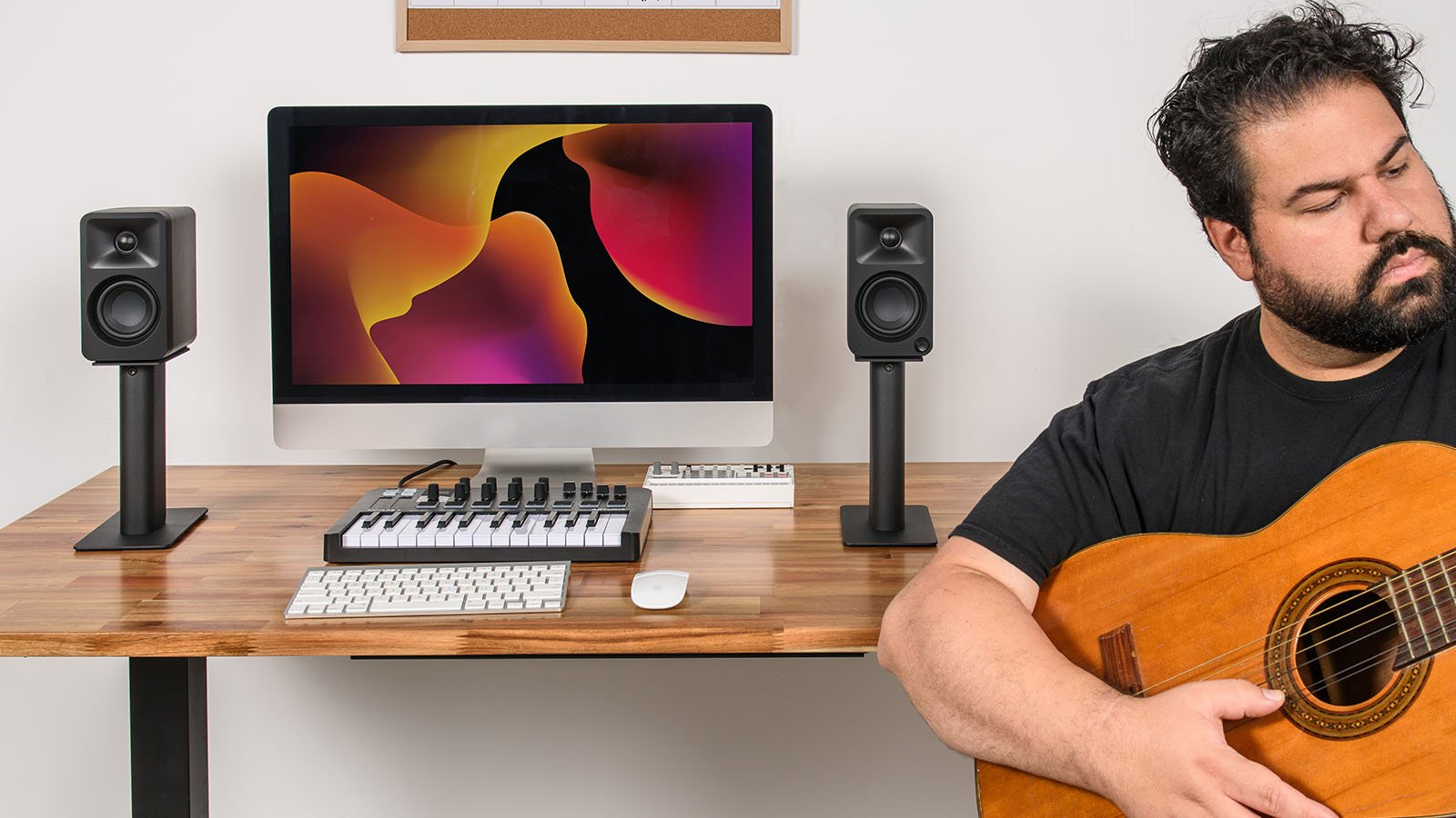 Kanto Audio Ora desktop speakers on a musician's desk with audio equipment and a laptop in a modern workspace.