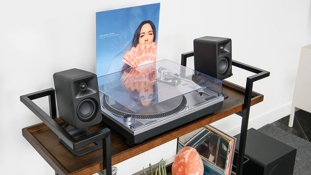 Kanto Audio Ora desktop speakers connected to turntable, showcasing stylish black design and audio setup on a modern desk.