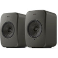 KEF LSX II LT active bookshelf speakers shown in a modern living room setup with sleek black design.