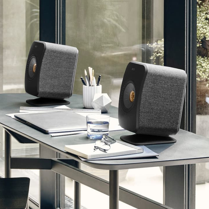 KEF LSX II wireless active bookshelf speakers in sleek black finish placed on a desk, showcasing modern audio design.
