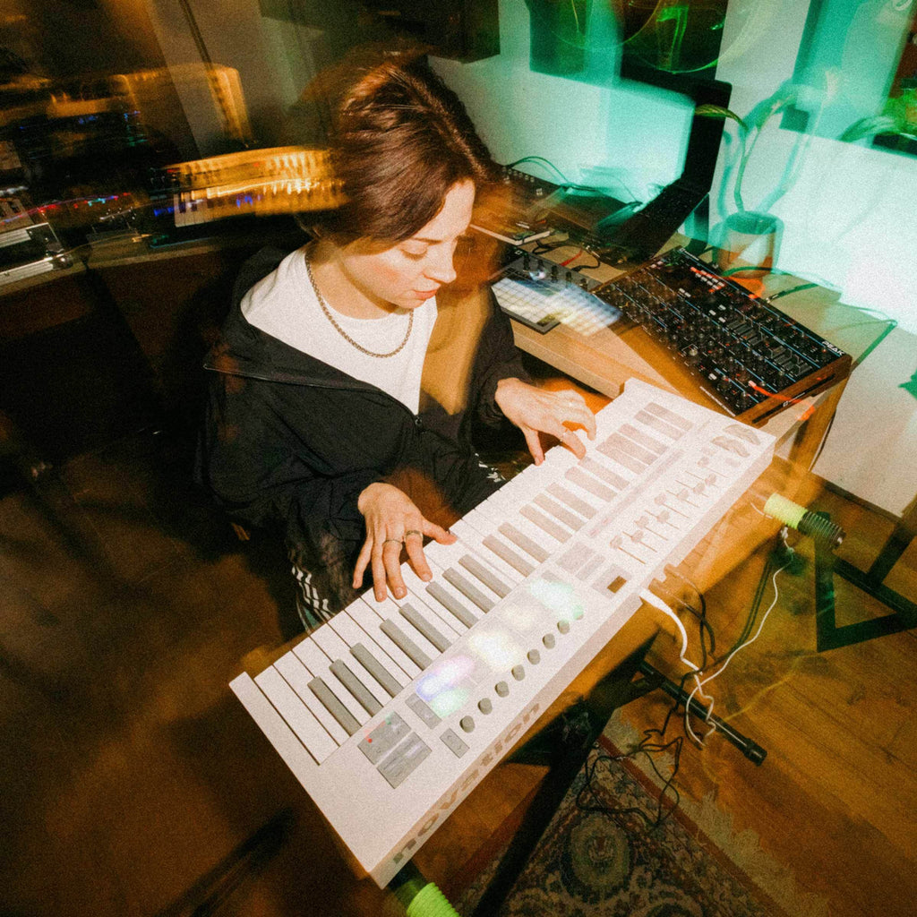 Novation Launchkey 49 MK4 MIDI keyboard with white finish, featuring keys, control knobs, and pads in a lifestyle setting.