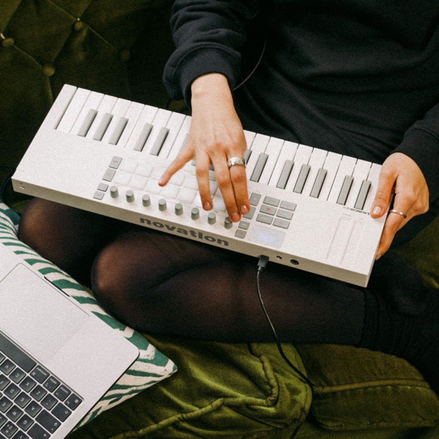 Novation Launchkey Mini 37 MK4 MIDI keyboard with white casing, shown in a lifestyle setting with keys and control knobs visible.