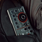 Numark Mixtrack Go tucked into a jacket pocket, showing its ultra-portable size