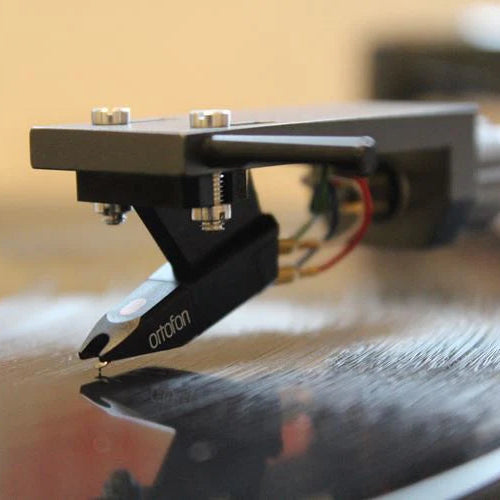 Ortofon OM 5E turntable cartridge mounted on a turntable, featuring a stylus for vinyl record playback.