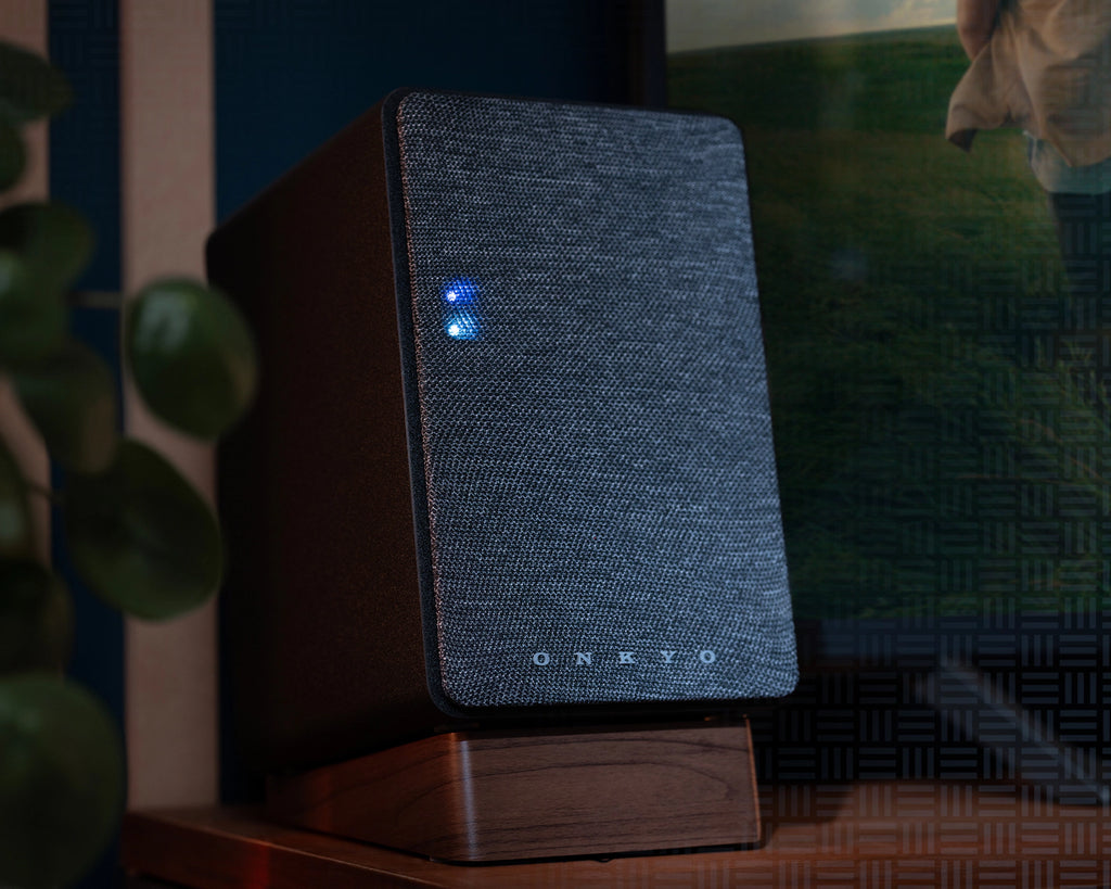 Close-up of Onkyo GX-30ARC desktop speakers with a plant in the background, highlighting sleek design and compact size.
