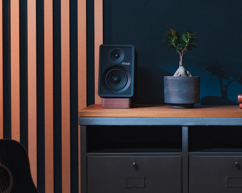 Onkyo GX-30ARC desktop speakers with near guitar on media console, showcasing compact design and sleek black finish.
