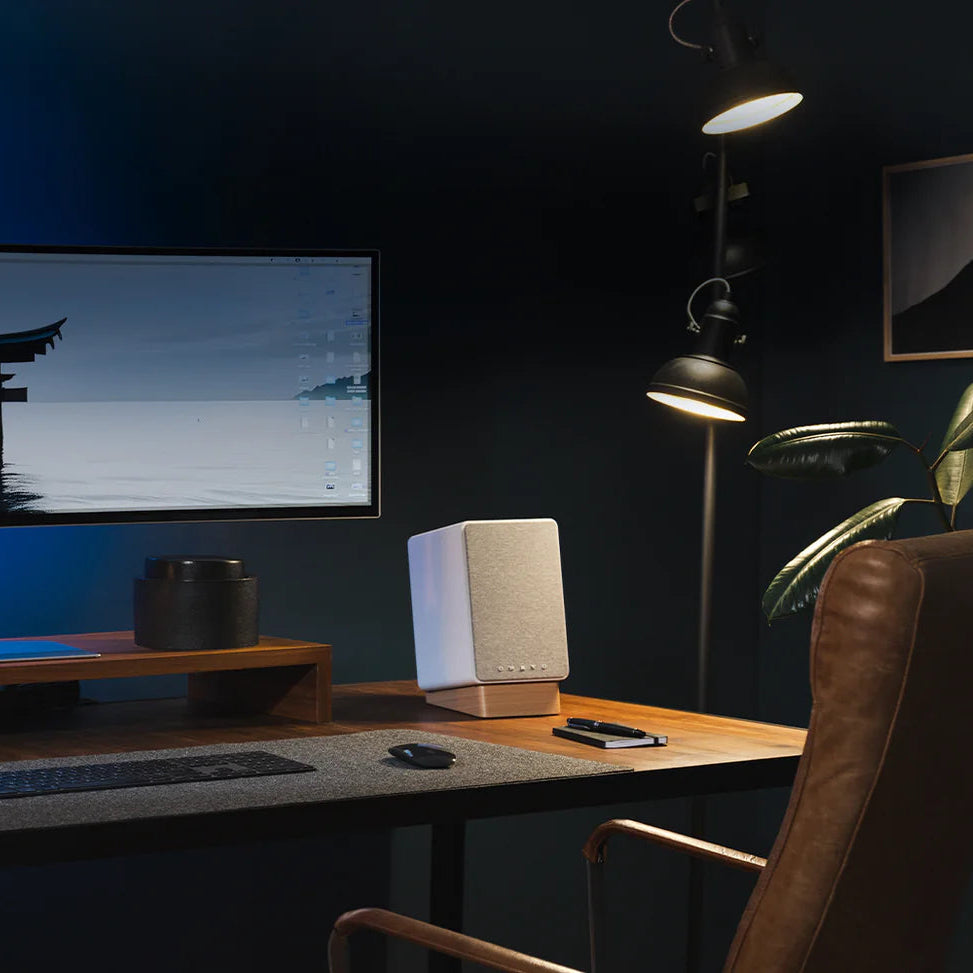 Onkyo GX-30ARC desktop speakers with white grilles on a desk in a dark blue office setting with moody lighting.
