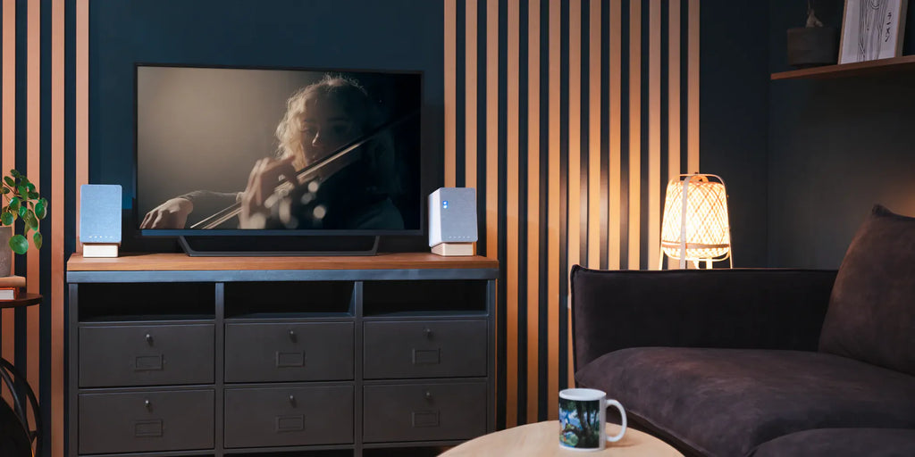 Onkyo GX-30ARC desktop speakers in a minimal living room setting with TV, showcasing sleek black design and compact size.