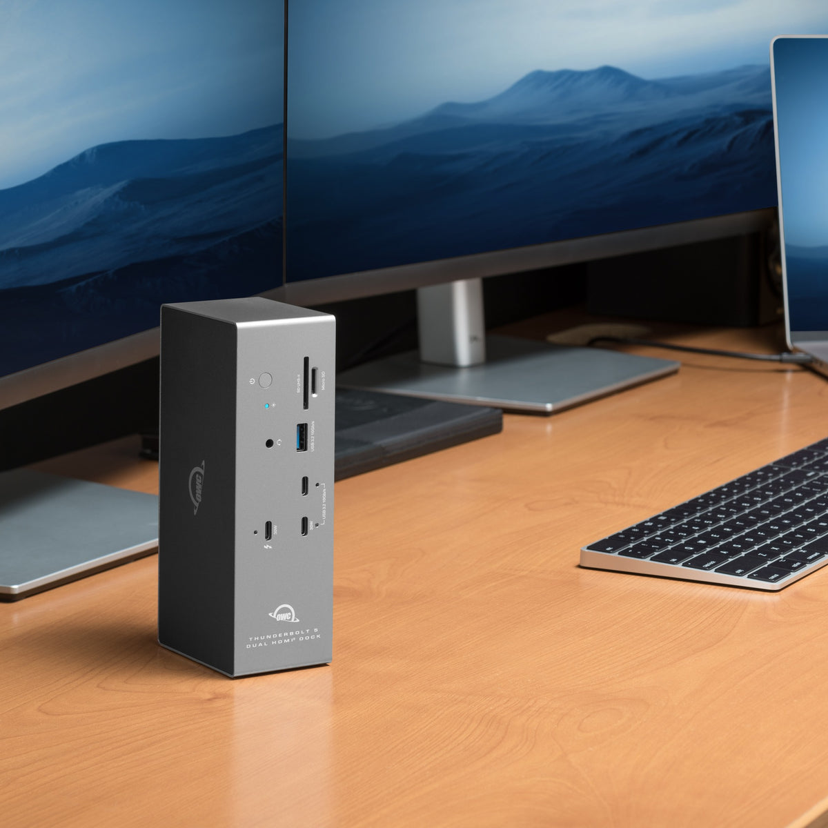 OWC Thunderbolt 5 Dock with Dual HDMI, standing vertically on a desk with dual monitors