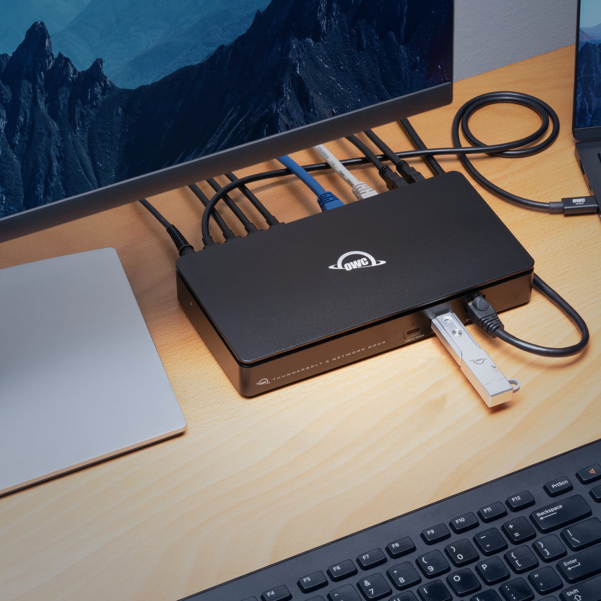 OWC Thunderbolt 5 Dual 10GbE Network Dock, on a desk connected to a monitor and keyboard