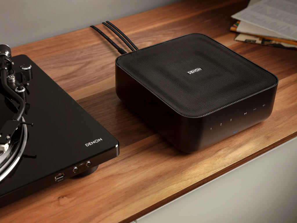 Denon Home Amp stereo amplifier showing front panel with control knobs and display screen, black finish, compact design.