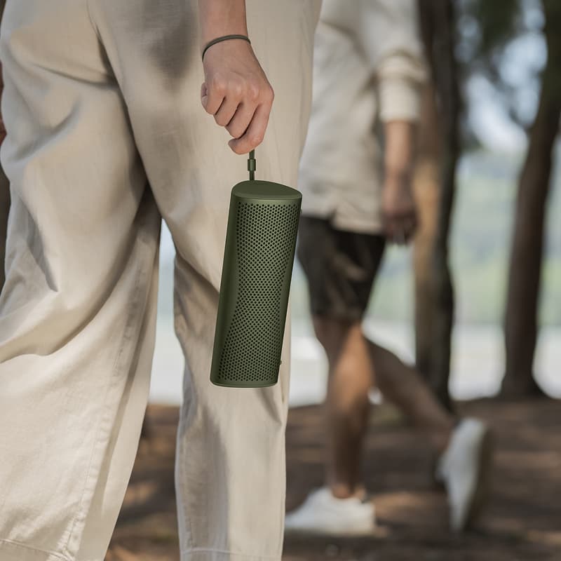 KEF Muo portable speaker in a modern outdoor setting, showcasing its sleek design and compact size for high-quality sound.