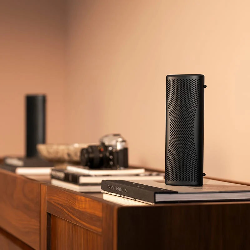 KEF Muo portable speaker shown in a lifestyle setting with sleek design and compact size, ideal for on-the-go music listening.