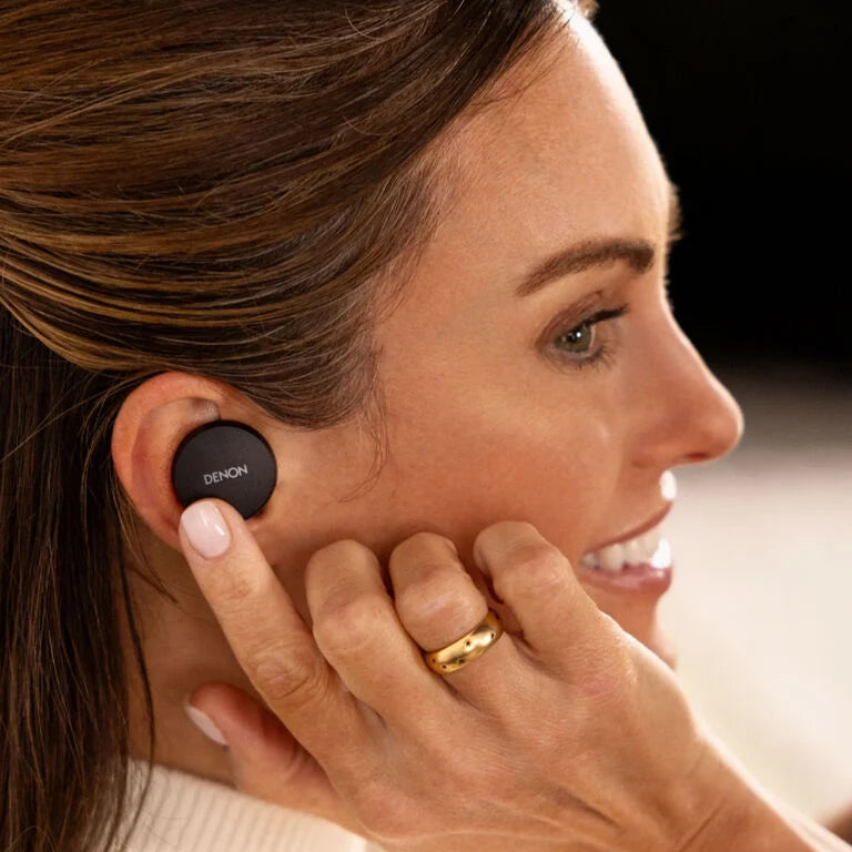 Wireless in-ear headphones by Denon, stylish design with earbuds and charging case, shown in a lifestyle setting.