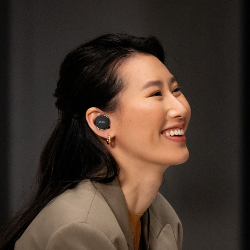 Denon PerL PRO wireless in-ear headphones with sleek black design and ergonomic ear tips, shown in lifestyle setting.