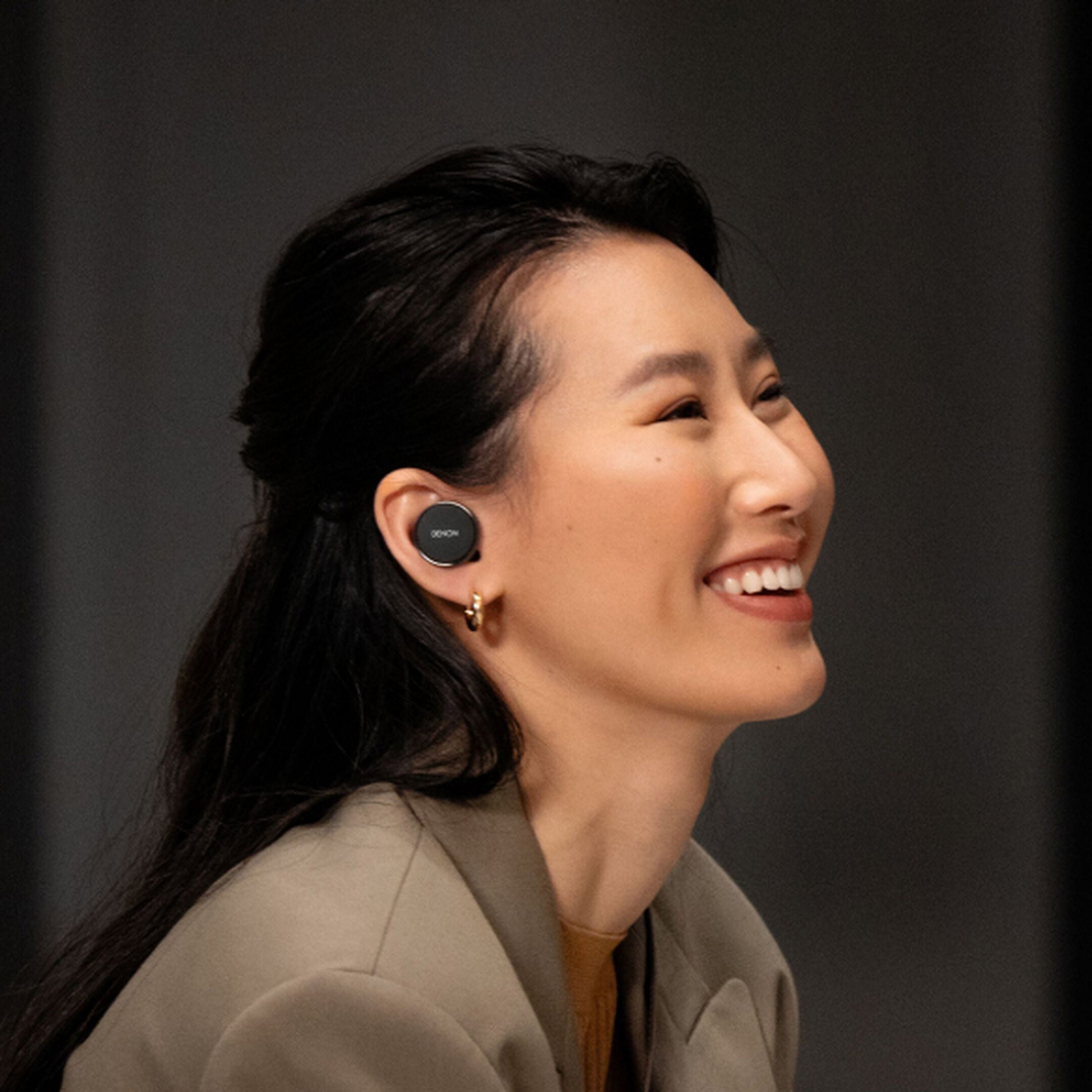 Denon PerL PRO wireless in-ear headphones with sleek black design and ergonomic ear tips, shown in lifestyle setting.