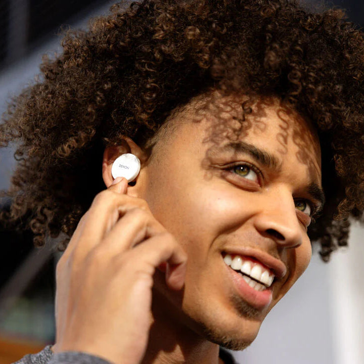 Denon PerL PRO wireless in-ear headphones with sleek black design and in-ear earbuds, shown in a close-up image.