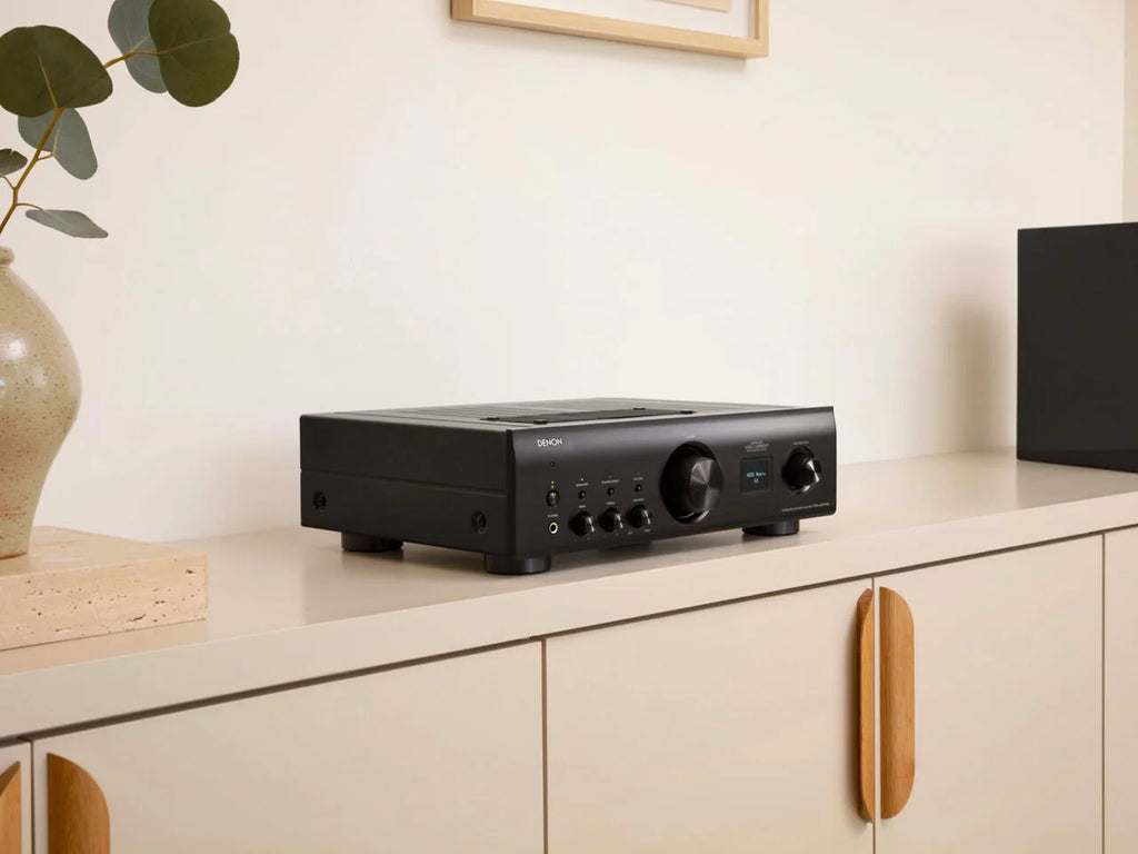 Denon PMA-900HNE stereo amplifier with silver finish and multiple input options, shown from a side-angle view.