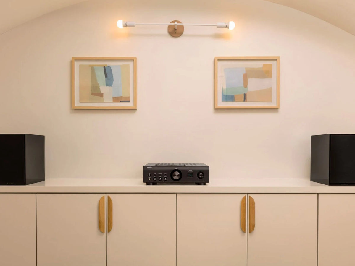Denon PMA-900HNE stereo amplifier with black metal finish, featuring control knobs and connection ports on front panel.