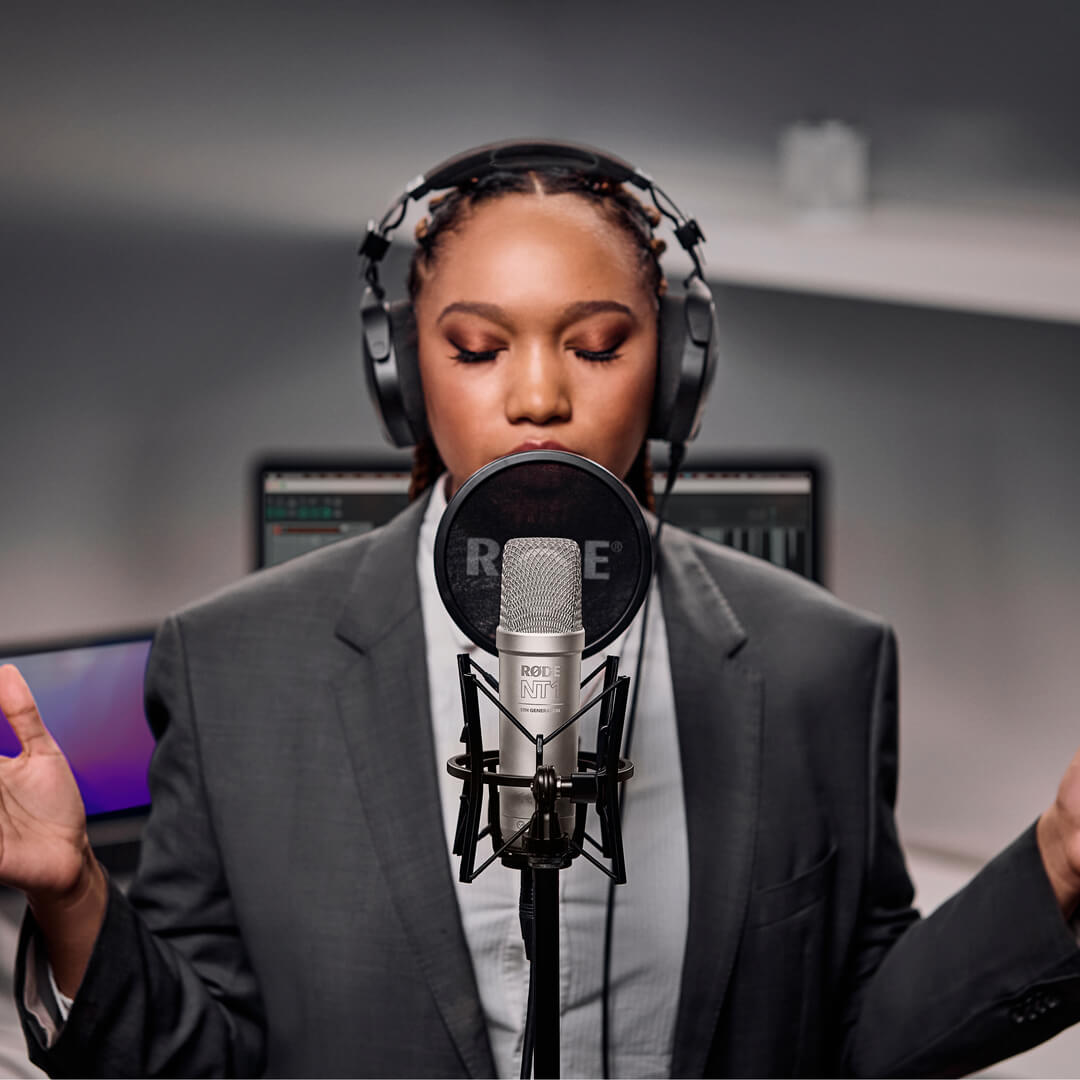 Rode NT1 GEN5 condenser microphone with silver finish, shown close-up in a home studio setup with XLR connection.