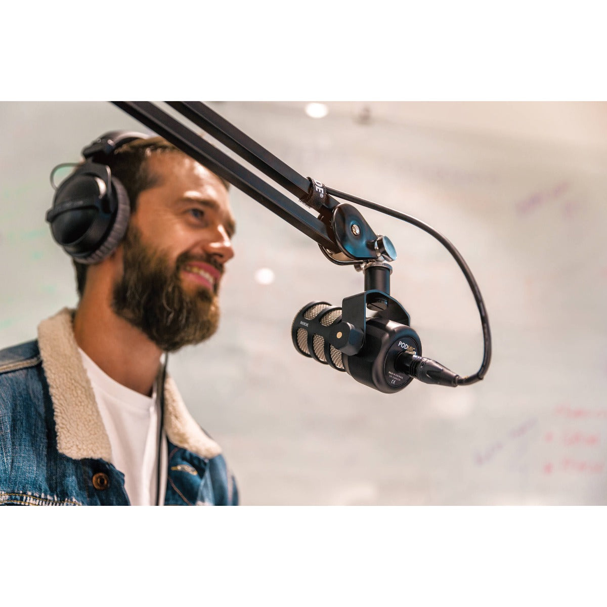 Rode PodMic dynamic microphone with black grille and body, mounted on a stand, suitable for podcasting and broadcasting.