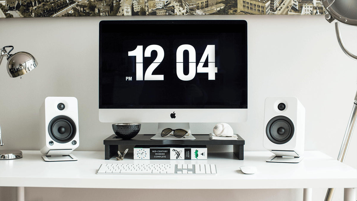 Kanto Audio S4 desktop speaker stands holding and elevating small bookshelf speakers on a desk.