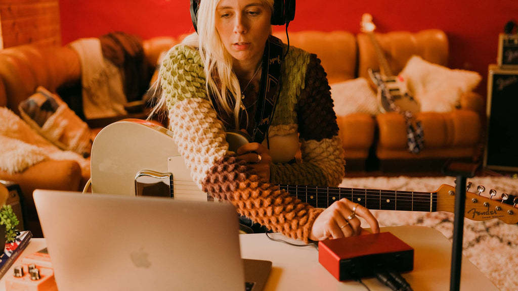 Focusrite Scarlett Solo 4th Gen audio interface with guitar connected, shown in a lifestyle setting.