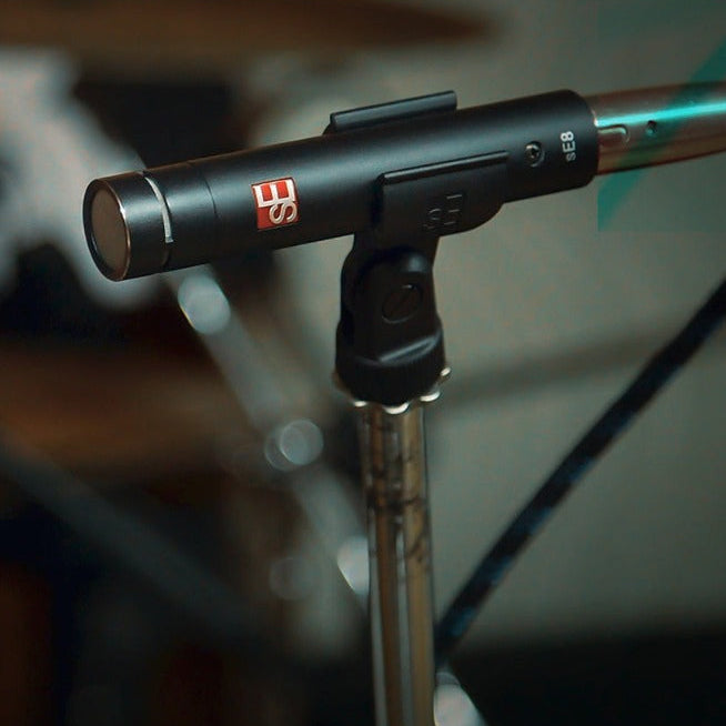 Pair of SE Electronics sE8 condenser microphones, stereo setup with black microphone bodies and gold-plated capsules on stands.