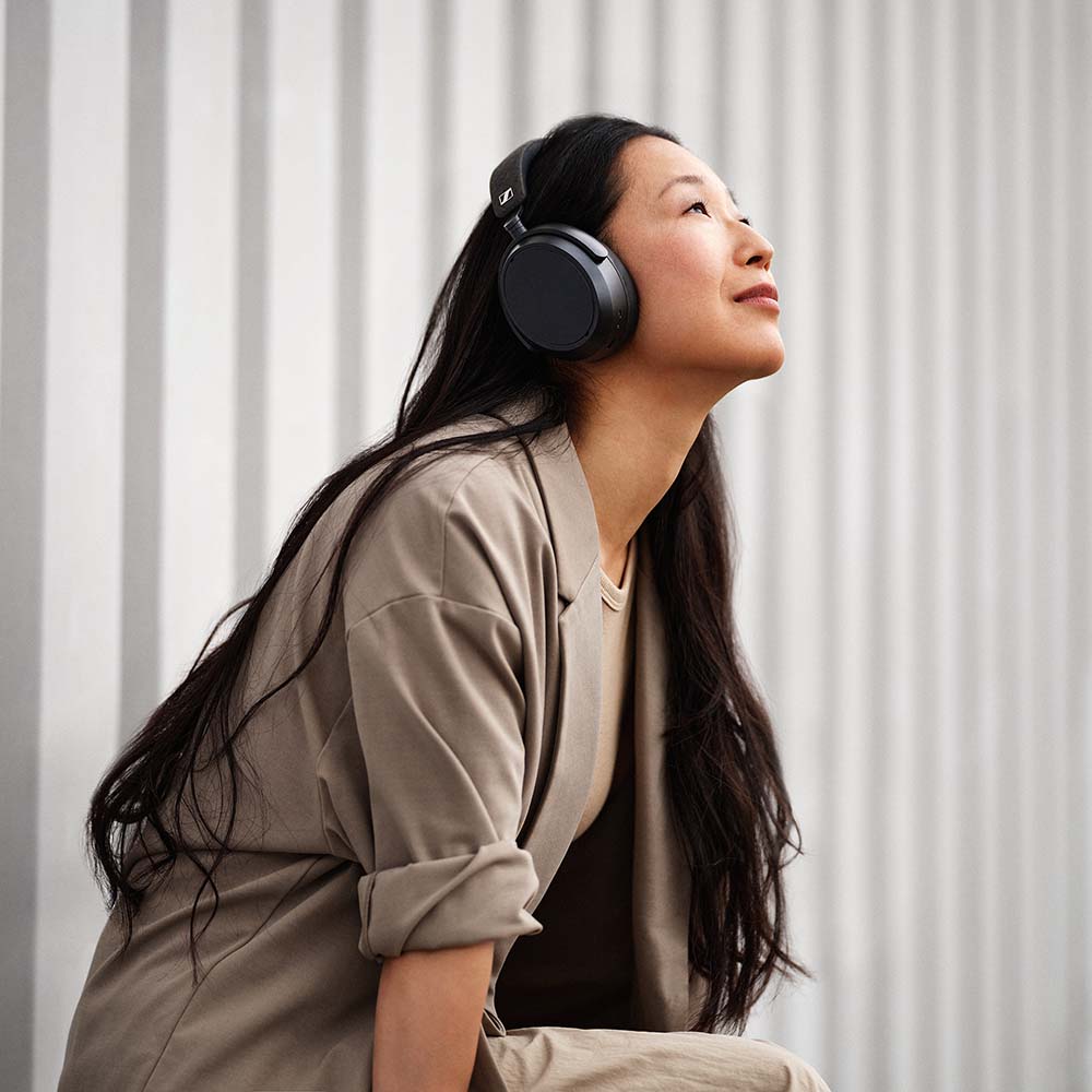 Black Sennheiser Momentum 4 Wireless headphones worn by a woman, showcasing sleek over-ear design and comfortable fit.
