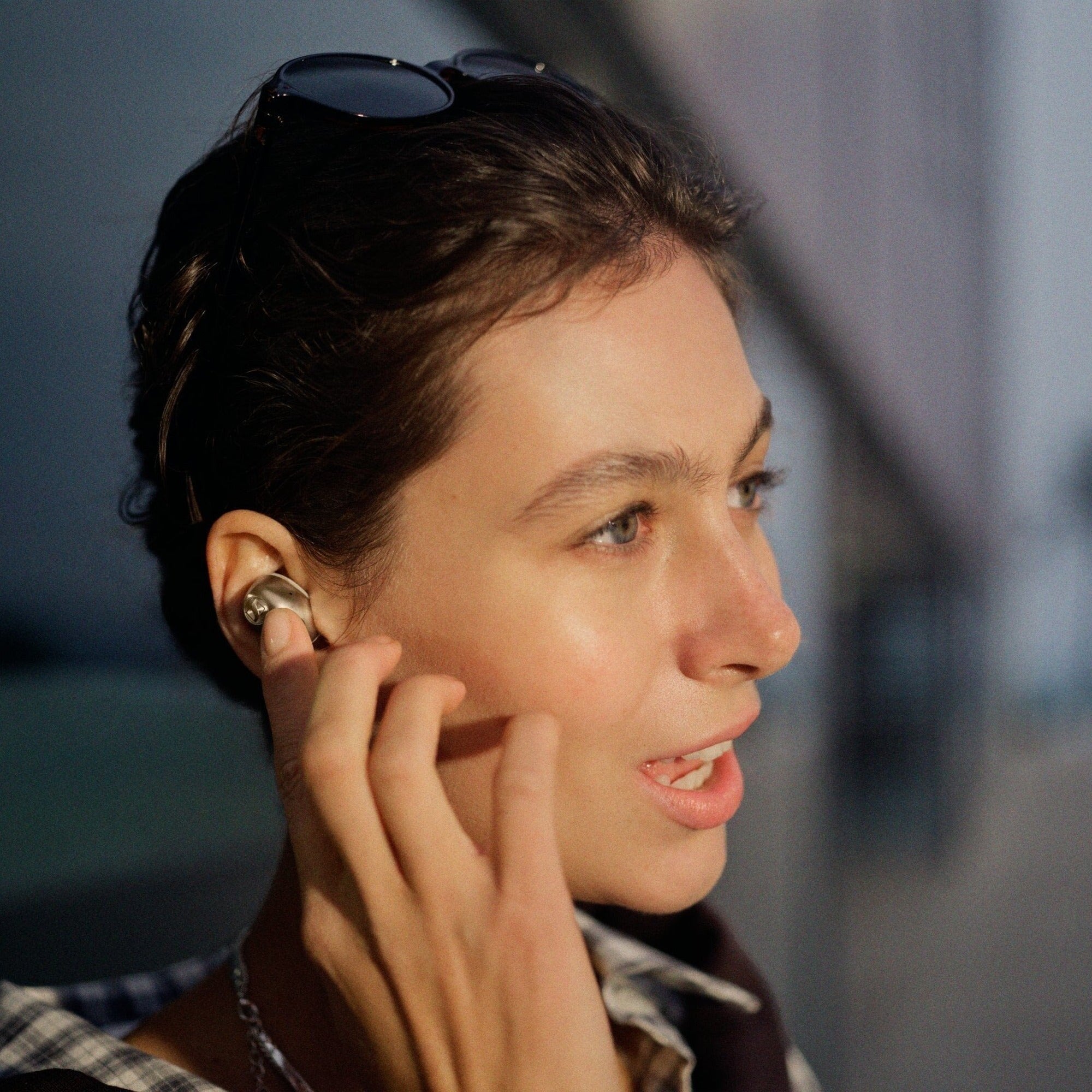 Sennheiser Momentum True Wireless 5 earbud worn in ear, evening lifestyle shot