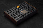 Erica Synths SYNTRX II desktop synthesizer with knobs and patch points on a black panel, showcasing its electronic interface.