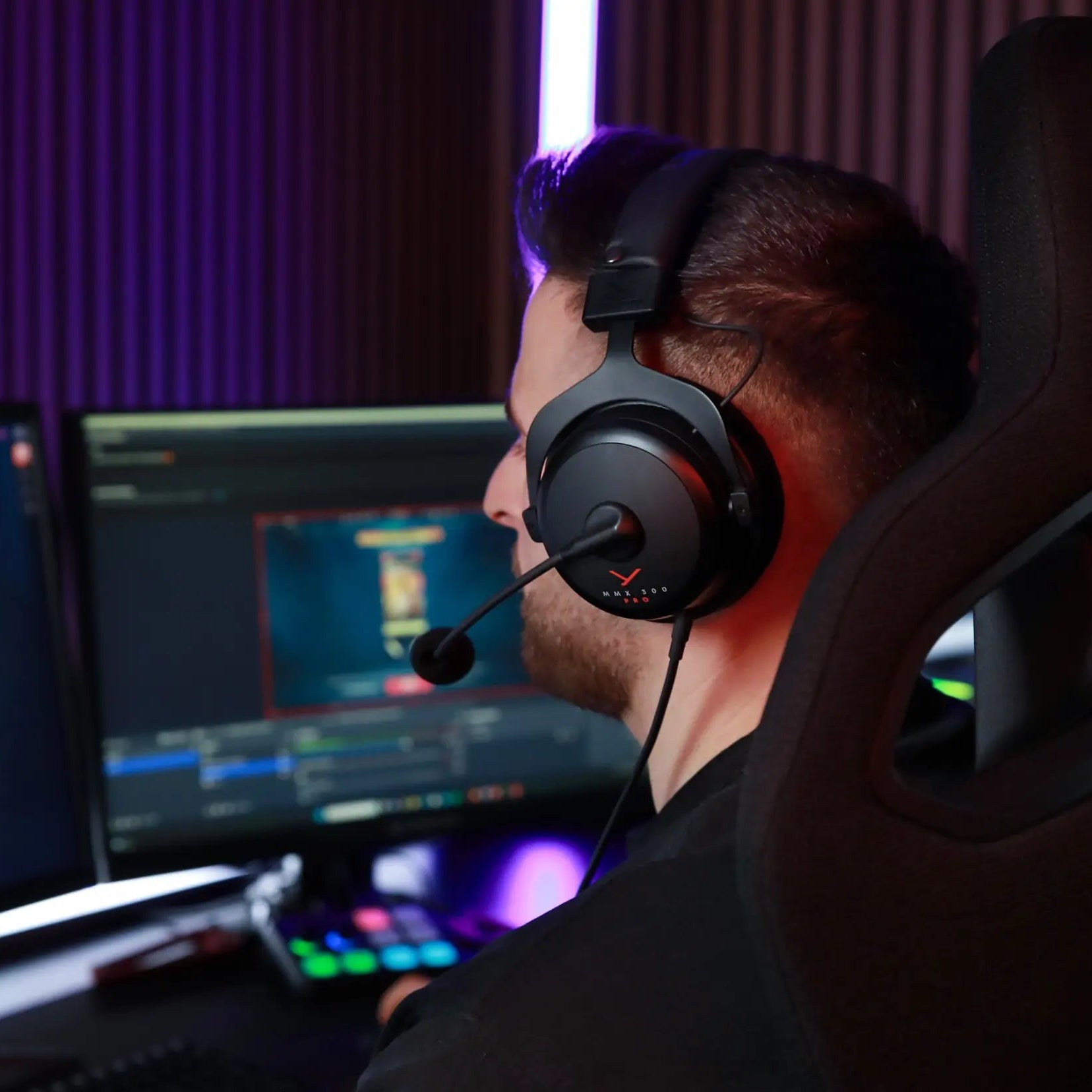 Beyerdynamic MMX 300 Pro gaming headphones with over-ear design, black color, worn by a gamer at a PC.