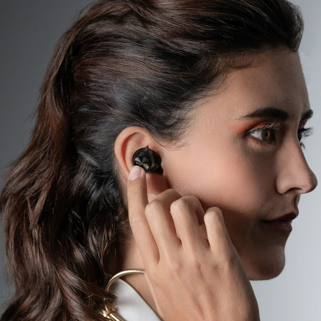 Black Technics EAH-AZ100 wireless in-ear headphones worn by a woman, with touch controls and sleek design.
