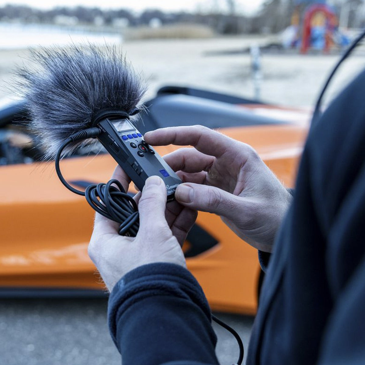 Zoom WSH-1e recorder accessory in use, showing its flexible microphone windscreen and shock mount for professional audio recording.